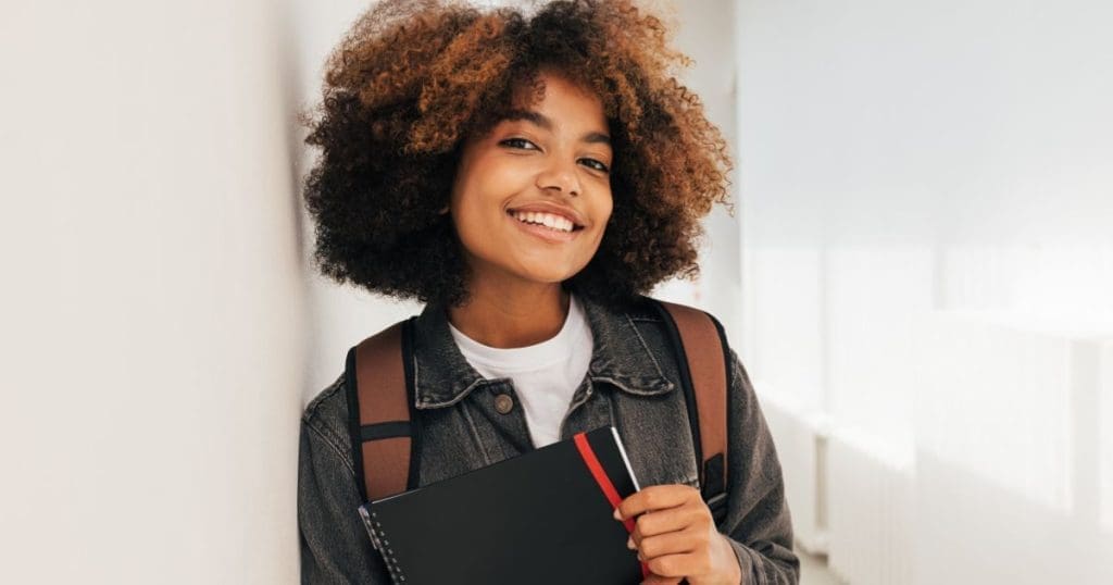 Cursos Técnicos - Retrato de uma bela estudante encostada uma parede e olhando para a câmera